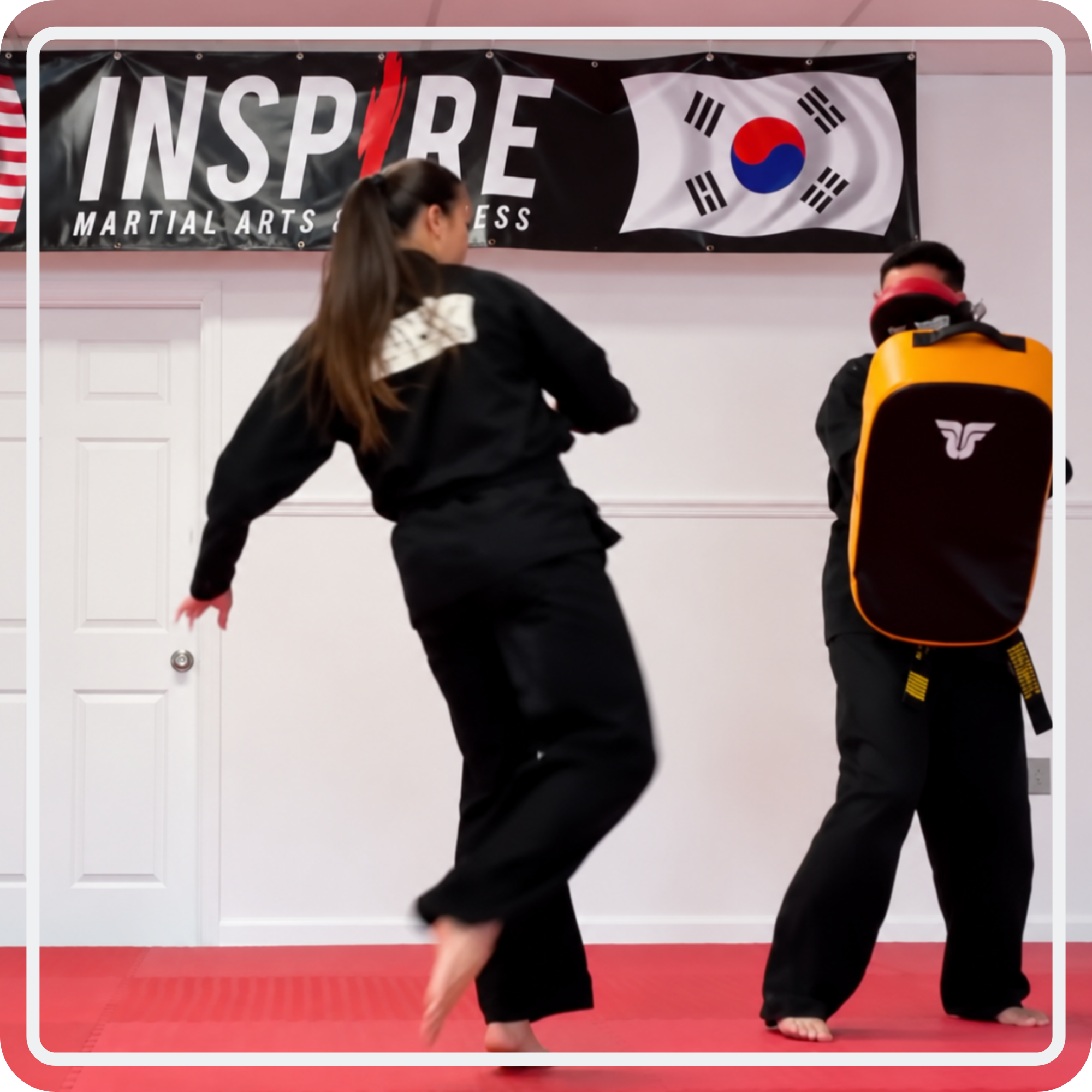 An Inspire student practicing a kick with an instructor holding a training shield